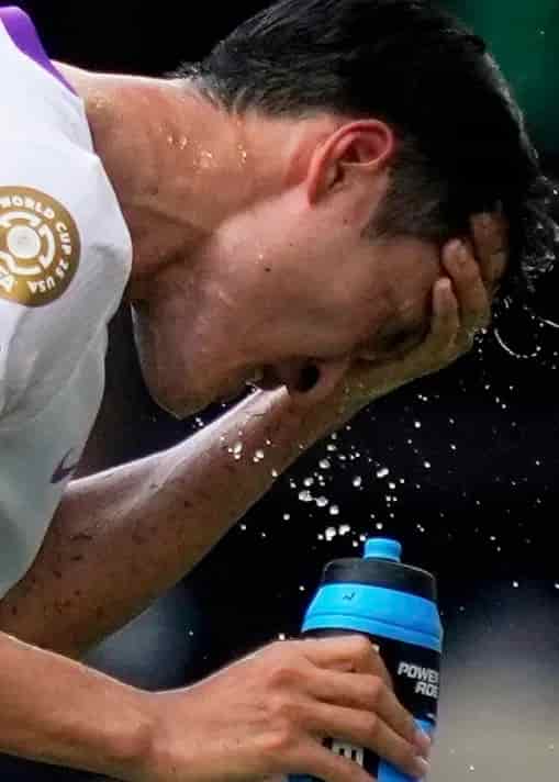 A soccer player hydrates during a break in the action.